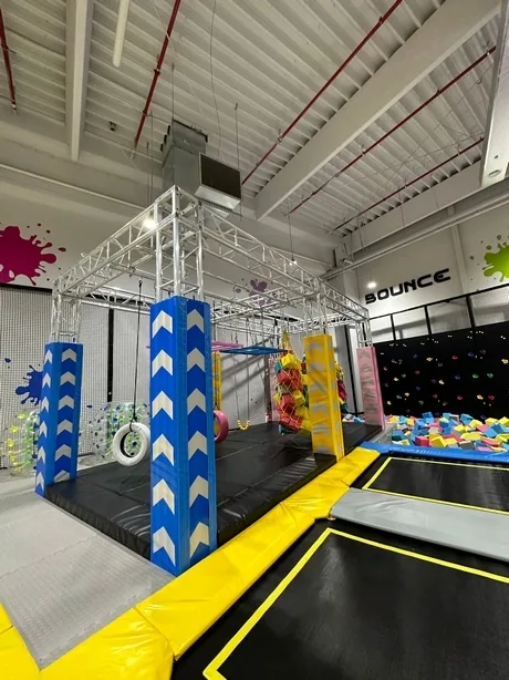 Băiat care trece peste obstacolele traseului Ninja, sub plasa de siguranță.